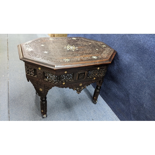 207 - A late 19th/early 20th century Middle Eastern heavily carved occasional table having mother of pearl... 