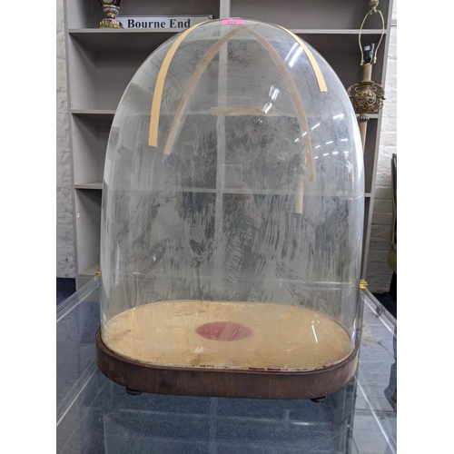 274 - A late 19th/early 20th century glass dome on an oval base supported on squat ball feet, 68cm h Locat... 