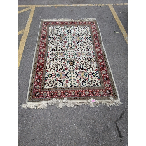 35 - A Persian Tabriz rug with a red floral border, and a symmetrical design with plants and flowers in b... 