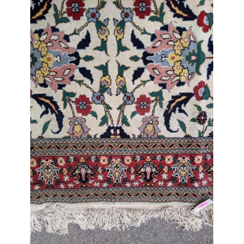 35 - A Persian Tabriz rug with a red floral border, and a symmetrical design with plants and flowers in b... 