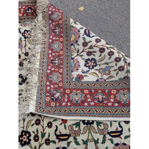 35 - A Persian Tabriz rug with a red floral border, and a symmetrical design with plants and flowers in b... 