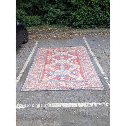 36 - A Caucasian Kazak rug decorated with three central motifs and a repeating abstract blue and cream bo... 