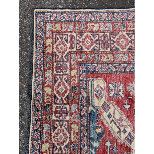 36 - A Caucasian Kazak rug decorated with three central motifs and a repeating abstract blue and cream bo... 