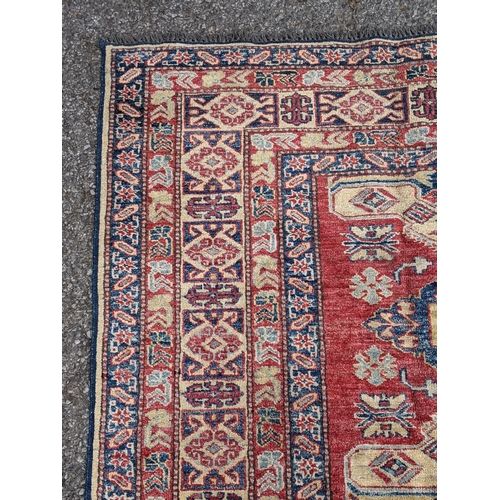 36 - A Caucasian Kazak rug decorated with three central motifs and a repeating abstract blue and cream bo... 