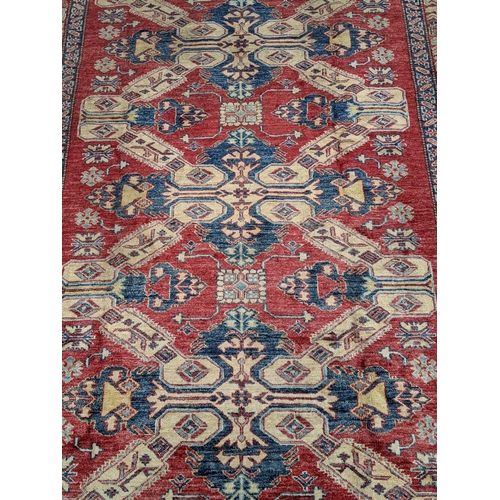 36 - A Caucasian Kazak rug decorated with three central motifs and a repeating abstract blue and cream bo... 