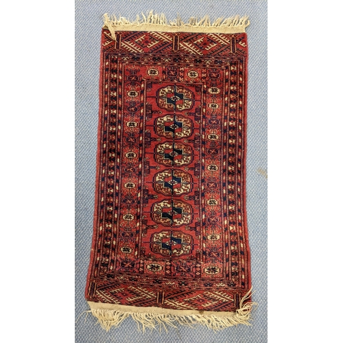 82 - A hand woven Persian design red ground small rug having elephant foot motifs and multiguard borders,... 