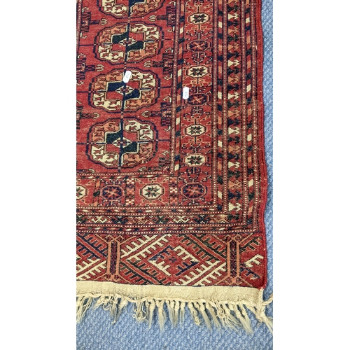 82 - A hand woven Persian design red ground small rug having elephant foot motifs and multiguard borders,... 