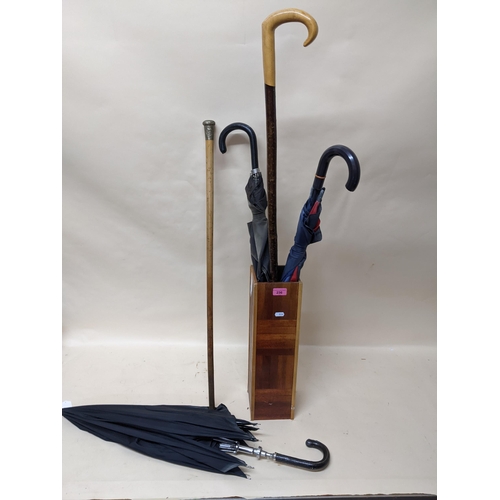 236 - A group of vintage umbrellas, a walking stick, and a swagger stick in a wooden stick stand to includ... 