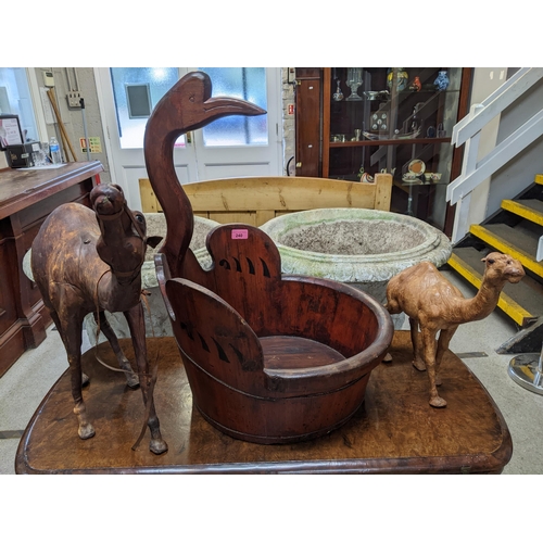 240 - A wooden Chinese baby bath with shaped bird head handle, along with two leather camel models
Locatio... 