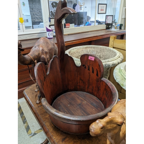 240 - A wooden Chinese baby bath with shaped bird head handle, along with two leather camel models
Locatio... 