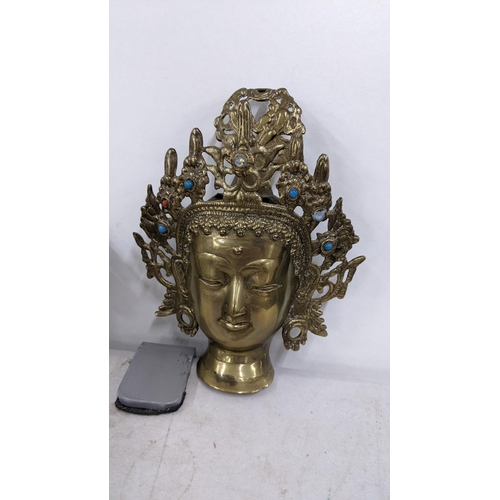 140 - An Oriental gilt metal incense burner cast as the head of Mahakala, together with a Buddha head and ... 