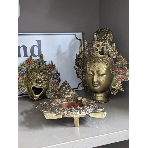 140 - An Oriental gilt metal incense burner cast as the head of Mahakala, together with a Buddha head and ... 