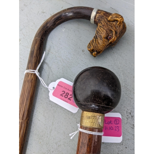 282 - Two walking sticks one with an added carved wooden dog head handle and the others, a bowling ball
Lo... 