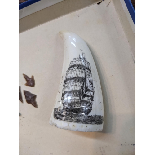 42 - A 20th century scrimshaw whale tooth tooled with image of a ship, together with possible flint and o... 