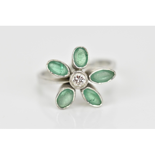 375 - A white metal, emeralds and diamond floral ring, with central bezel set brilliant cut diamond in a s... 