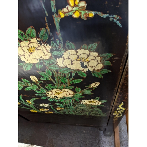 355 - A Chinese black lacquered and painted side cabinet with floral design to the lower doors, the upper ... 