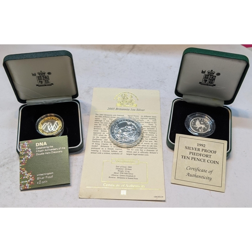 508 - A group of three UK silver proof coins to include the 2003 DNA £2 cased, 1992 10-pence coin, and a 2... 