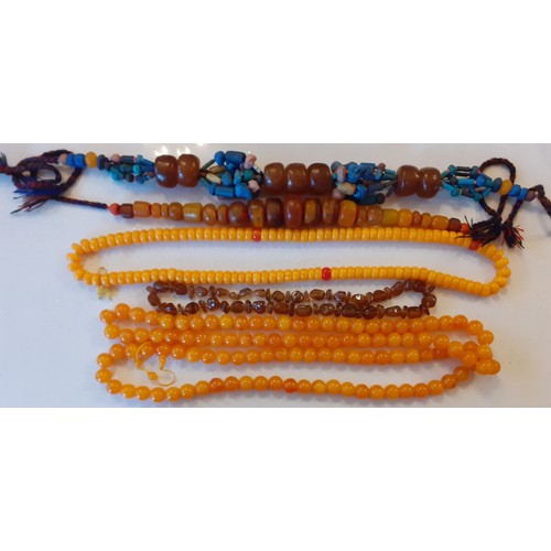 69 - A vintage brown amber necklace together with two native necklaces of reconstructed amber and other b... 