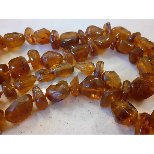 69 - A vintage brown amber necklace together with two native necklaces of reconstructed amber and other b... 