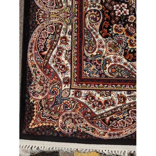 247 - A modern Persian style machine woven Elena rug, ornate design on a black ground, double guard border... 