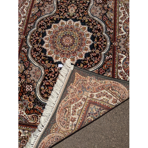 247 - A modern Persian style machine woven Elena rug, ornate design on a black ground, double guard border... 