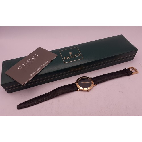 126 - Gucci-A gents gold plated wristwatch having a black leather strap with original guarantee and box. L... 