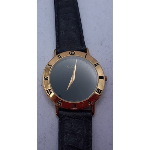 126 - Gucci-A gents gold plated wristwatch having a black leather strap with original guarantee and box. L... 