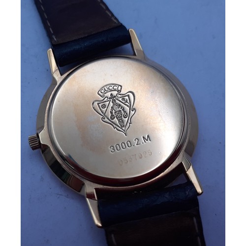 126 - Gucci-A gents gold plated wristwatch having a black leather strap with original guarantee and box. L... 