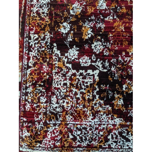 103 - A contemporary small floral patterned machine woven rug on a red ground 147cm x 92cm Location:G