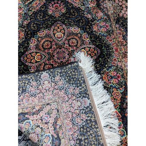 105 - A contemporary small Persian style rug, machine woven on a black ground, floral pattern with a borde... 