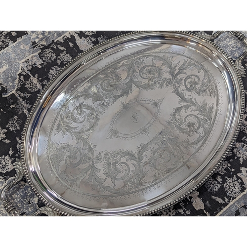 55 - A large twin handled oval silver plated serving tray, engraved with floral decoration and a central ... 