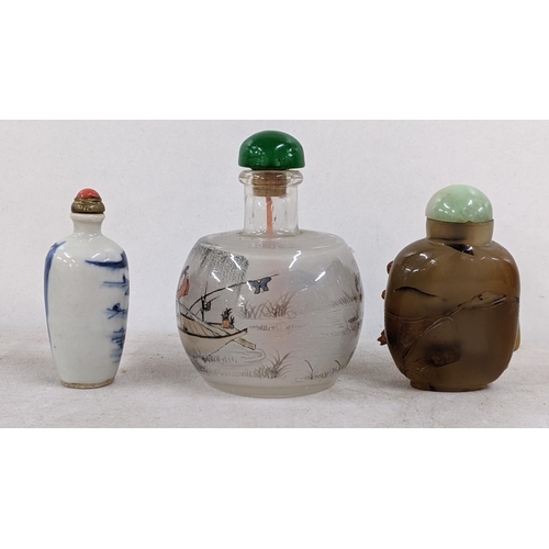 44 - Three Chinese snuff bottles to include a brown agate relief  carved bottle decorated with a cat and ... 