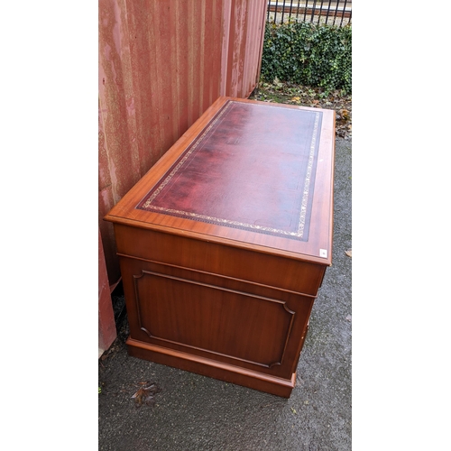 91 - A reproduction mahogany twin pedestal desk having a red leather top above nine drawers 79cm h x 152c... 