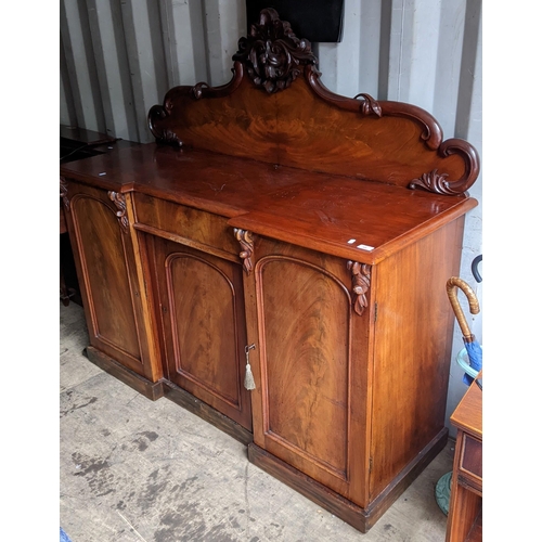 94 - A Victorian mahogany sideboard having a raised carved back, central drawer and three cupboard doors ... 