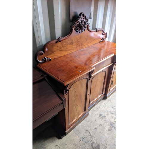 94 - A Victorian mahogany sideboard having a raised carved back, central drawer and three cupboard doors ... 