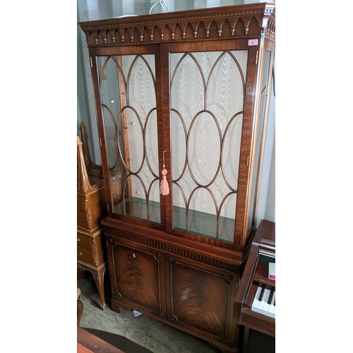 96 - A reproduction mahogany display cabinet having a dental moulded cornice above two glazed and two cup... 