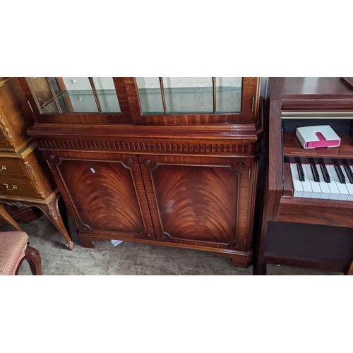 96 - A reproduction mahogany display cabinet having a dental moulded cornice above two glazed and two cup... 