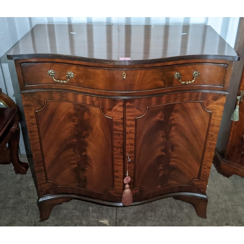 99 - A reproduction mahogany serpentine fronted cabinet having a single drawer above two cupboard doors, ... 