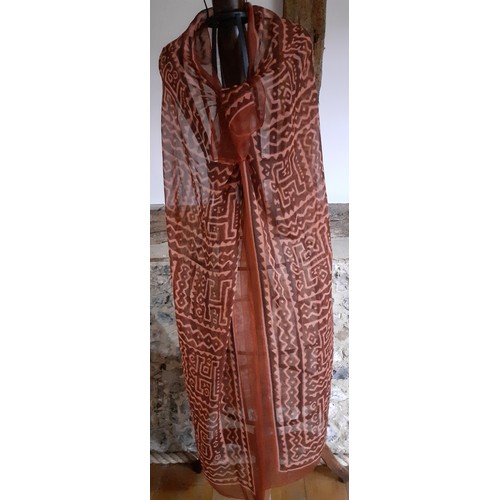 140 - Hermes- A fine silk chiffon wrap in rust and salmon colours, having large capital letters within the... 