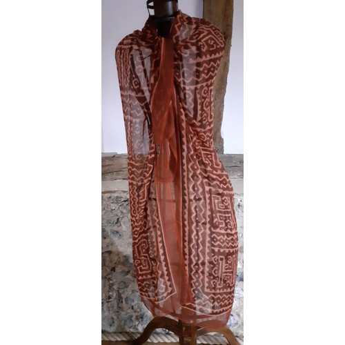 140 - Hermes- A fine silk chiffon wrap in rust and salmon colours, having large capital letters within the... 