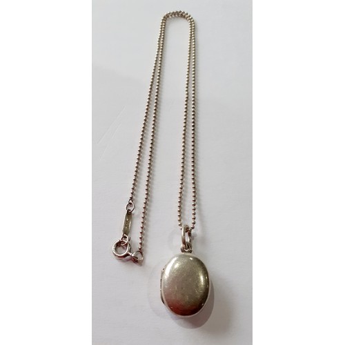 141 - Tiffany-A silver necklace having a ball chain and a small oval shaped locket with makers mark stampe... 