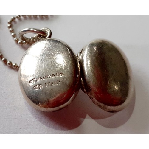 141 - Tiffany-A silver necklace having a ball chain and a small oval shaped locket with makers mark stampe... 