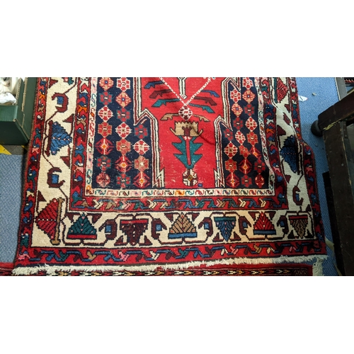 414 - An Iranian hand woven runner having a red ground with a central motif, repeating patterns and tassel... 