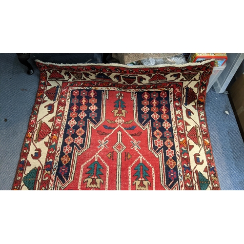 414 - An Iranian hand woven runner having a red ground with a central motif, repeating patterns and tassel... 