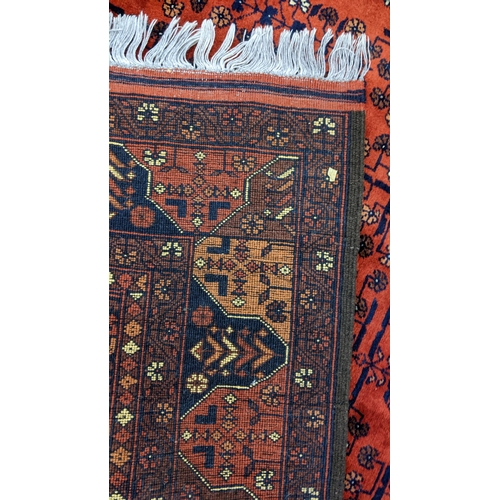 415 - A Persian hand woven rug having a floral design on a red ground and multi-guard borders, 162cm x 189... 