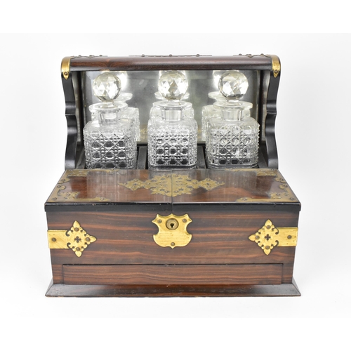 202 - A late Victorian brass-clad coromandel veneered tantalus, comprising three cut glass decanters, mirr... 