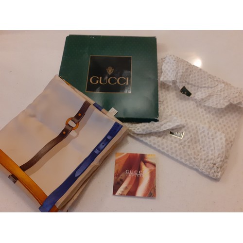 11 - Gucci- A late 20th Century silk scarf having a tan ground with images of horse leathers, belts and s... 