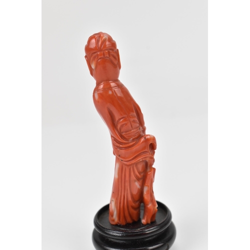 154 - A Chinese Qing dynasty carved red coral model of an official, 19th century, holding a document in hi... 