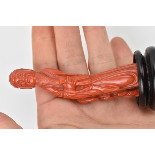 154 - A Chinese Qing dynasty carved red coral model of an official, 19th century, holding a document in hi... 