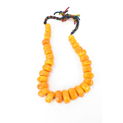 192 - A large Moroccan pressed amber bead necklace, with graduated block beads on string, wool fastening, ... 